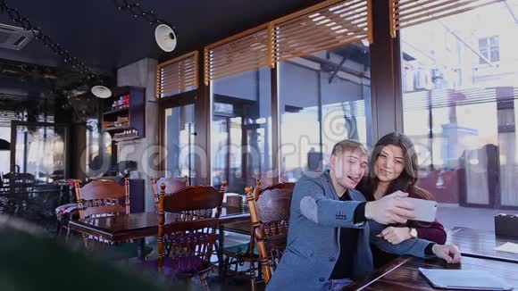 一对情侣在咖啡厅正面对着智能手机摄像头自拍视频的预览图