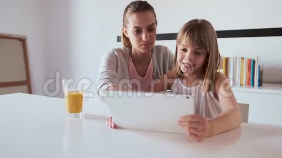 年轻漂亮的母亲和女儿在家里用数码平板电脑视频的预览图