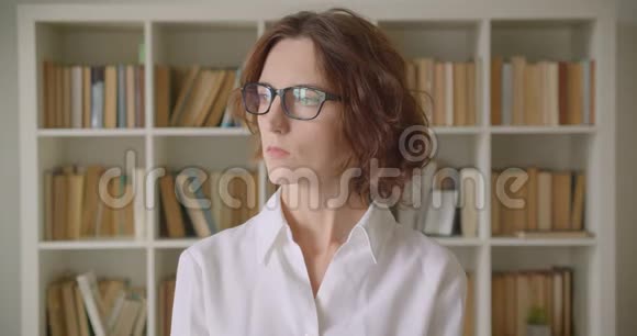 一位戴着眼镜看着室内摄像机的白种人成年红发美女特写镜头视频的预览图