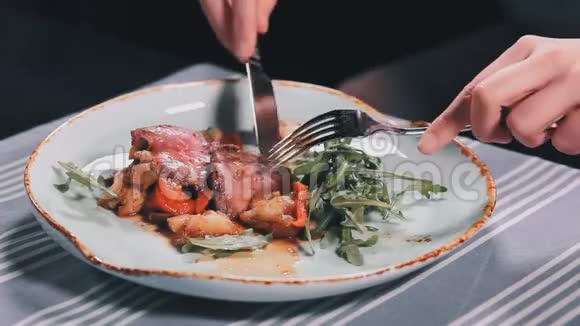 餐馆餐桌上用刀叉切肉的女人的手视频的预览图