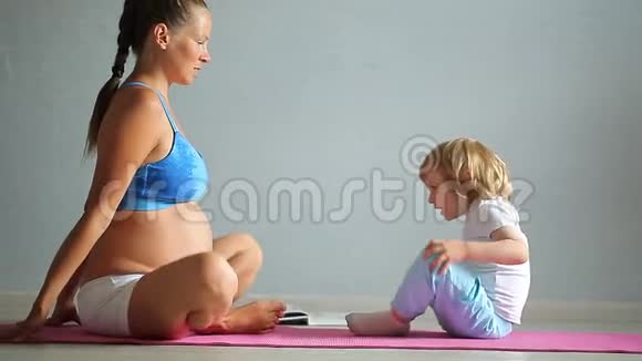 怀孕的女孩早上在家做瑜伽视频的预览图