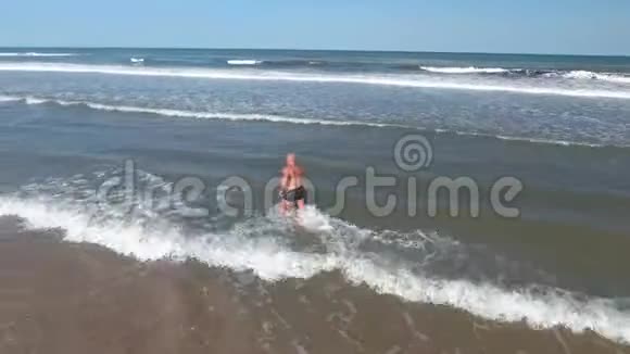 这位运动员沿着海滩沿着海岸在水中奔跑视频的预览图