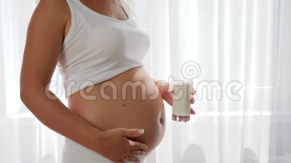 孕妇持有玻璃牛奶并在肚子奶制品背景上签字认可视频的预览图
