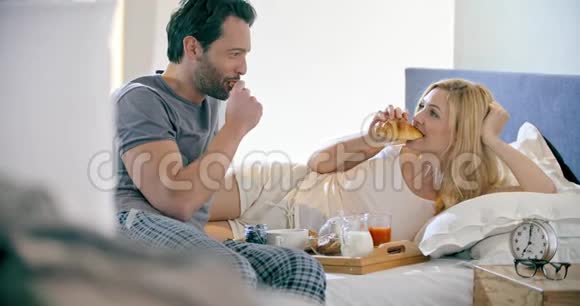 美丽的男人和女人在床上吃早餐恋爱中的情侣早晨在卧室的家里醒来视频的预览图