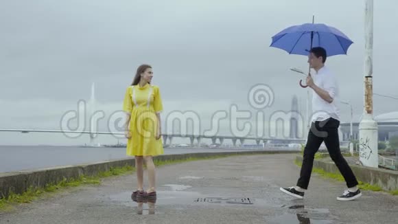 一对年轻夫妇在海上海岸的一个码头上在伞地跳舞视频的预览图