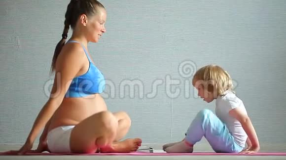 怀孕的女孩早上在家做瑜伽视频的预览图