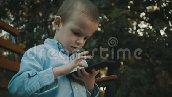 小男孩在户外的智能手机上玩电子游戏视频的预览图