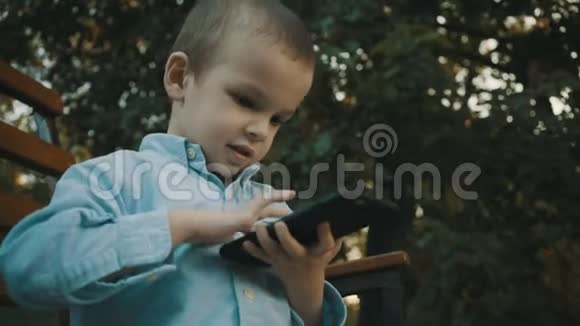 小男孩在户外的智能手机上玩电子游戏视频的预览图