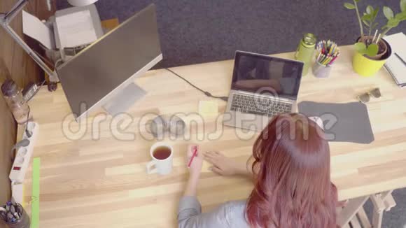 女商人在她的工作场所做纸笔喝茶视频的预览图