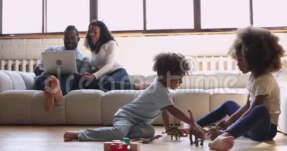 带孩子的非裔美国人父母在客厅里放松视频的预览图