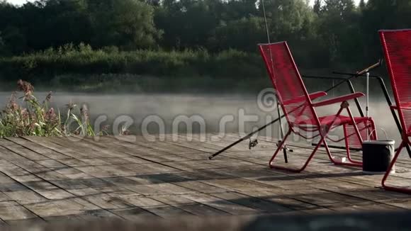 两张红色的椅子站在渔墩上背景是清晨的雾水面上视频的预览图