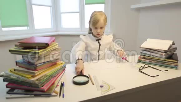 漂亮的女学生坐在办公桌前拿着书看着大放大镜视频的预览图