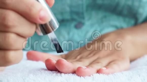 女人在家修指甲时在指甲上涂透明指甲漆女人把指甲擦得紧紧的家庭修指甲及视频的预览图