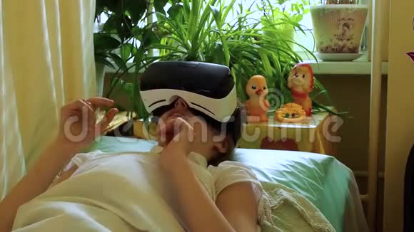 悲伤生病的白种人女孩躺在病床上躺在一条毯子下戴着VR眼镜视频的预览图