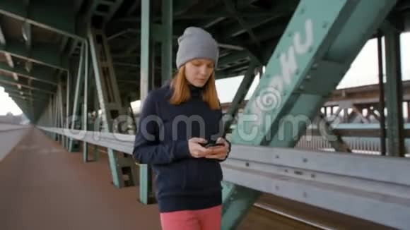 使用电话和乘坐电车穿越工业大桥的年轻女性视频的预览图