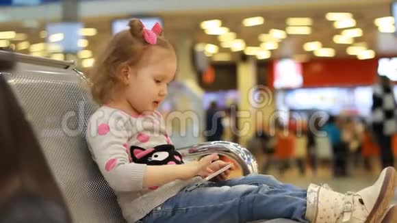 在机场候机楼里坐在候机室里的孩子在等待他们的航班时玩手机A视频的预览图
