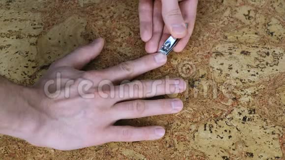 男人正在用剪刀在桌子上剪指甲特写手指木头背狗视频的预览图
