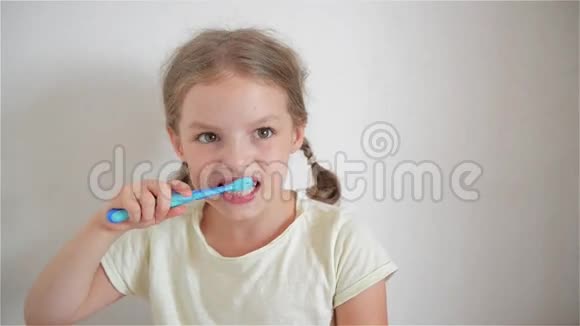 可爱的小女孩扎着辫子努力地刷牙在女孩手里有蓝色的牙刷快乐视频的预览图