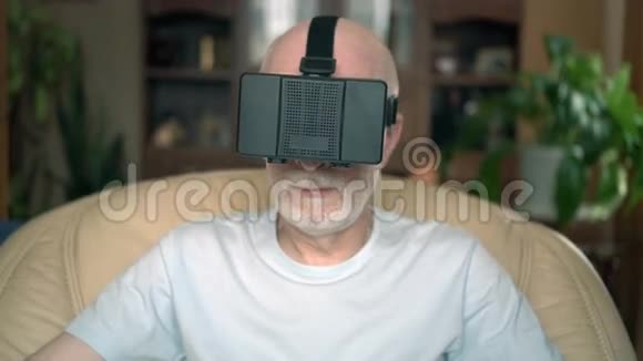 长得好看帅气微笑的学长坐在家里的椅子上使用虚拟现实眼镜视频的预览图