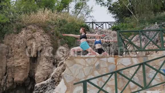 两个年轻女子在海边的高山悬崖上练习自然冥想视频的预览图