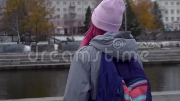 带背包的时髦女人的后视图特写一位年轻漂亮的女士她的头发是粉红色的帽子是粉红色的视频的预览图