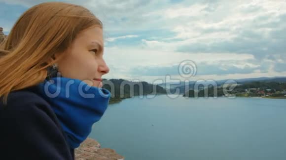 年轻的女人在湖边看着微笑着梦想着什么视频的预览图