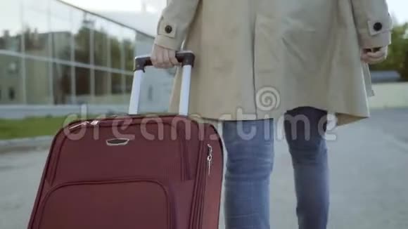 一个带着手提箱去机场大楼的女人视频的预览图