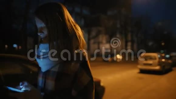 年轻女子走在黑暗的街道上发着短信微笑着视频的预览图