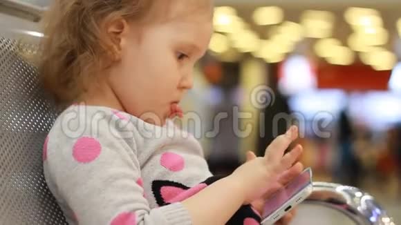 在机场候机楼里坐在候机室里的孩子在等待他们的航班时玩手机A视频的预览图