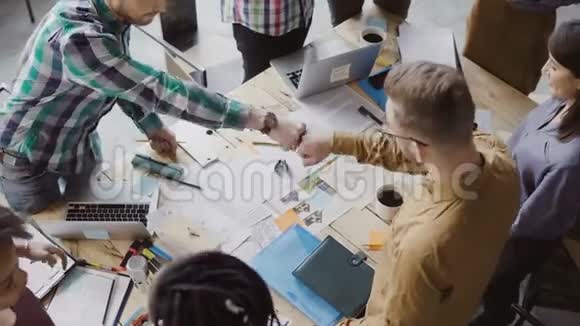 俯视年轻的商业团队一起工作在桌子附近集思广益两人拳头相迎视频的预览图