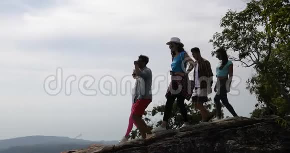 一群登山游客举着双手享受自由快乐的男人和女人在空中眺望风景视频的预览图