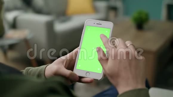 男手在客厅里用绿色屏幕的手机视频的预览图