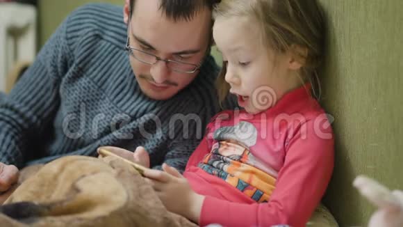 小女孩和爸爸在黑暗的房间里玩手机游戏视频的预览图