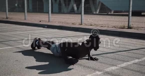 街头锻炼运动的非裔美国人在户外做俯卧撑和旋转运动一个黑人在玩视频的预览图