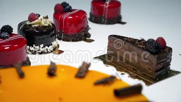 几块蛋糕躺在一张白色的桌子上一个糖果师用巧克力装饰一块蛋糕视频的预览图