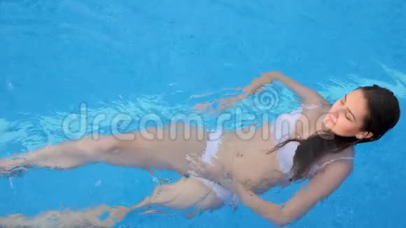 美丽的女性身材穿着白色泳装在夏日泳池边游泳视频的预览图
