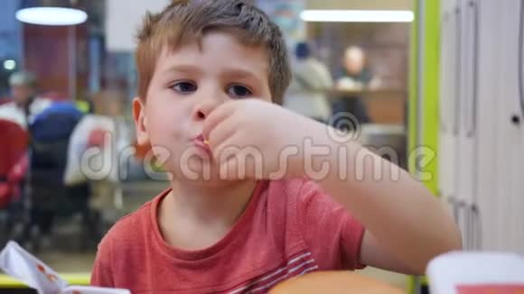 孩子在餐桌上玩有害食物汉堡和薯条作为儿子的零食在学校的自助餐厅里吃油性食物视频的预览图