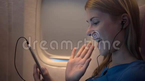 飞机窗户附近美丽迷人的女人长途飞行通过Skype与朋友交谈视频的预览图