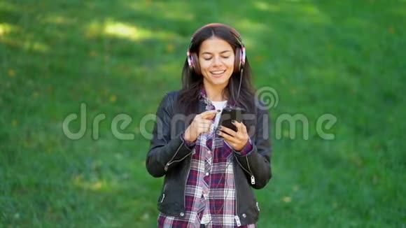 美丽的混合种族年轻女子听音乐耳机与智能手机西班牙的时髦女郎视频的预览图