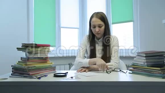 戴眼镜的年轻老师坐在桌子上和一个女学生说话视频的预览图