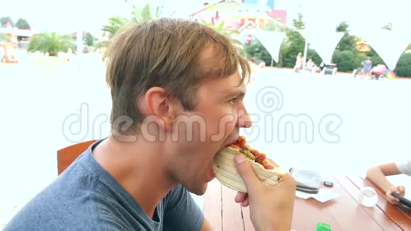 一个有魅力的人坐在一家快餐店里吃一个新鲜的面包皮塔里面有新鲜的蔬菜和肉沙拉视频的预览图