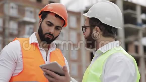 建筑工人和建筑师正在讨论站在附近的现代商务中心的建设计划视频的预览图