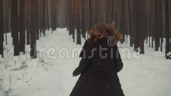 一个红发女孩在冬天的森林里出现精灵的肖像女孩穿过冬天的森林看上去视频的预览图