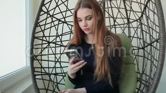 美丽的年轻女子坐在椅子上打电话视频的预览图