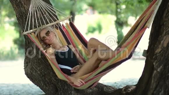 女人躺在沙滩上树影的吊床上视频的预览图