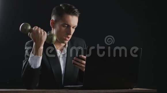 年轻的商人用手提电脑和哑铃做运动视频的预览图