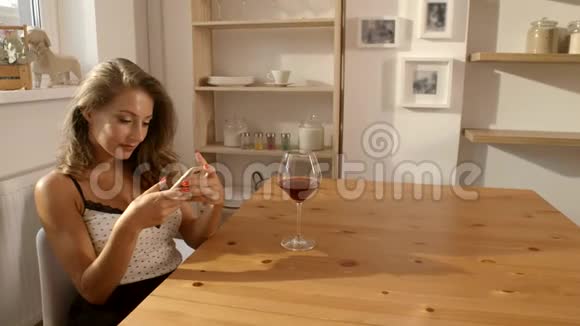 有魅力的女人穿着坦率的衣服坐在一家咖啡馆里喝着一杯红酒发短信视频的预览图
