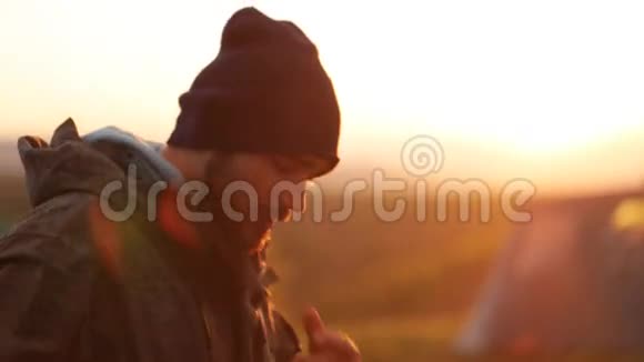 日落野营时留胡子的英俊男子的肖像视频的预览图