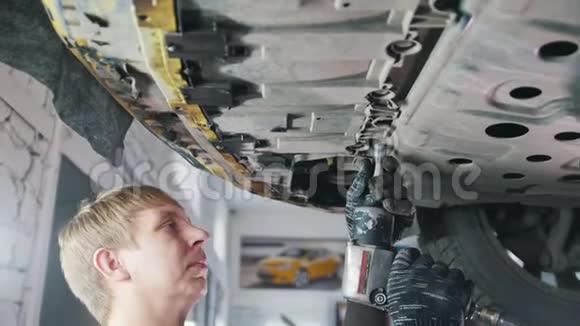 汽车服务机械手在车辆底部拧下汽车细节视频的预览图