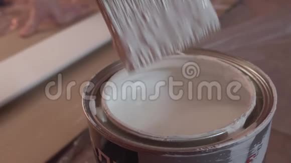 画家用手把刷子蘸在桶里涂上白色油漆动作缓慢视频的预览图